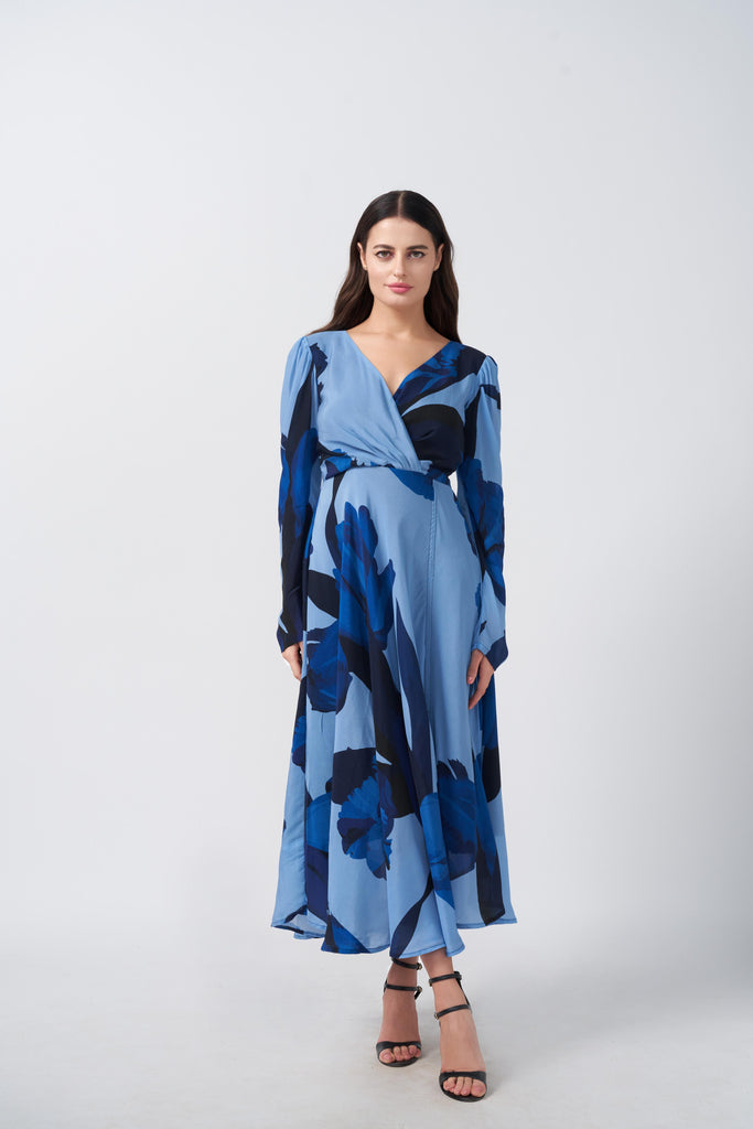 Model standing front-facing in light and dark blue floral crepe dress with overlap V-neck and long sleeves.