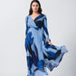 Model mid-step in flared blue floral dress, showcasing movement and slit detail.