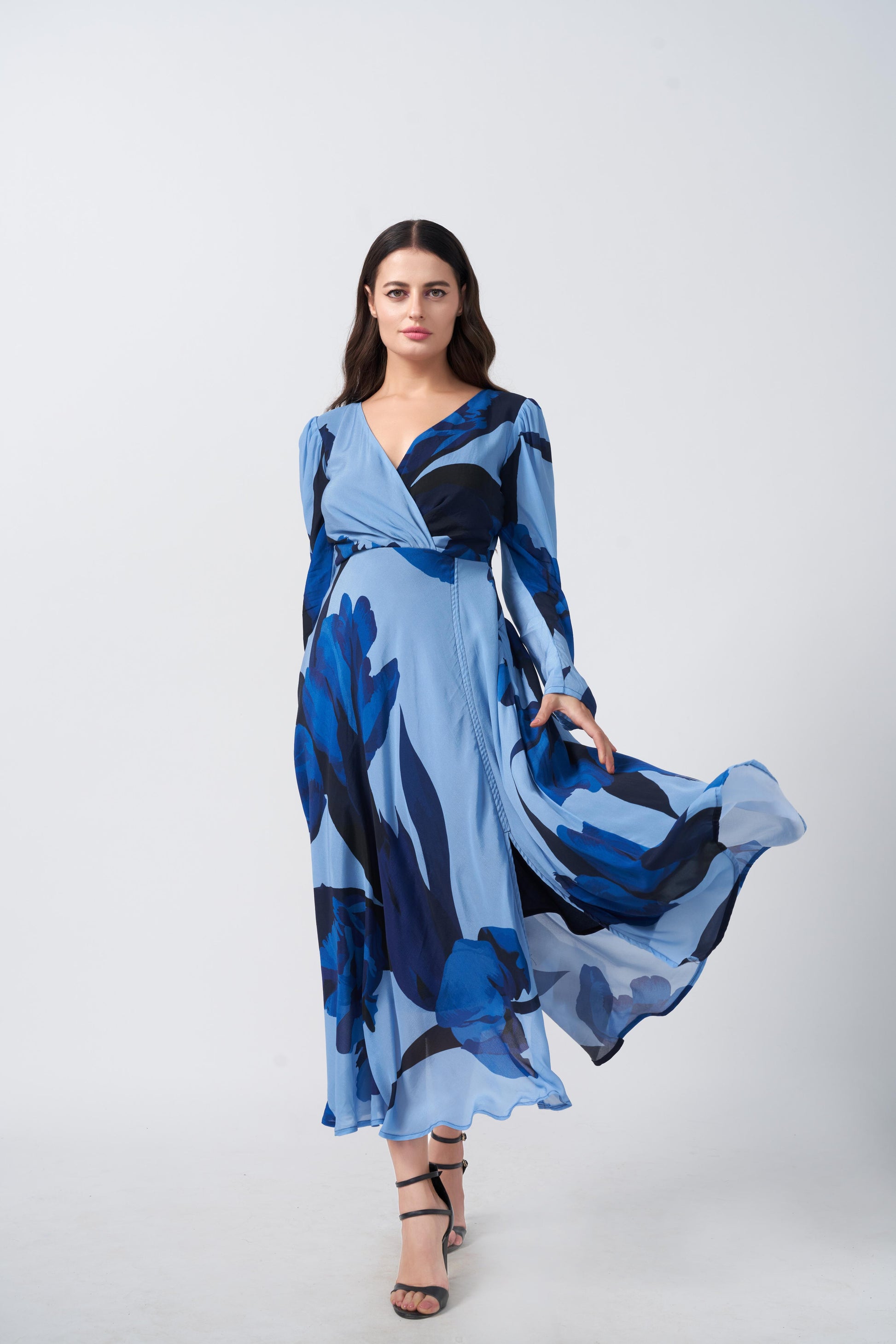 Model mid-step in flared blue floral dress, showcasing movement and slit detail.