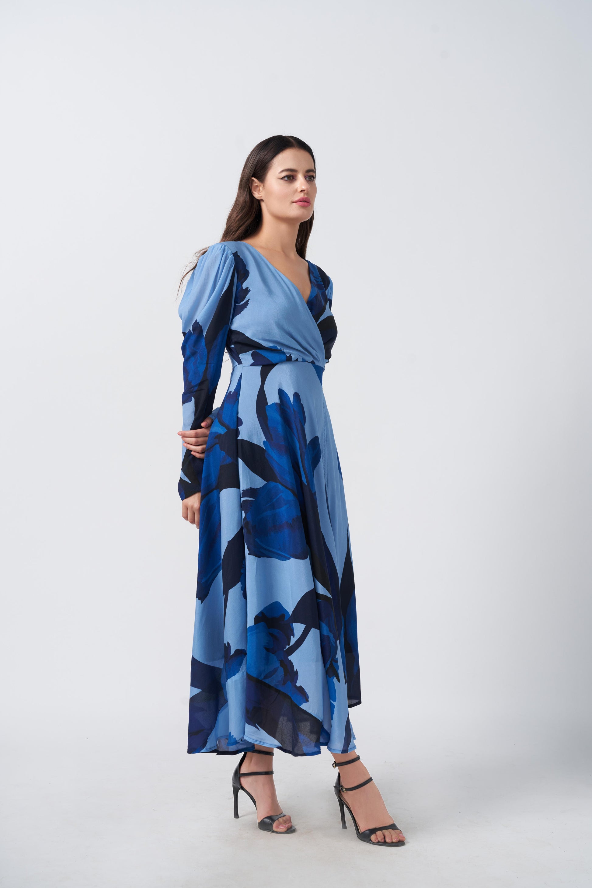 Walking view of model in blue floral crepe dress, showcasing ankle-length flow and slit detail.