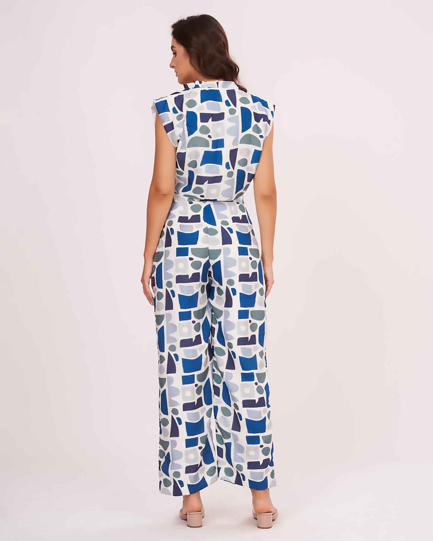 Rear view of the blue V-neck crop top and matching printed trousers, highlighting the back button and relaxed straight-leg pant fit.