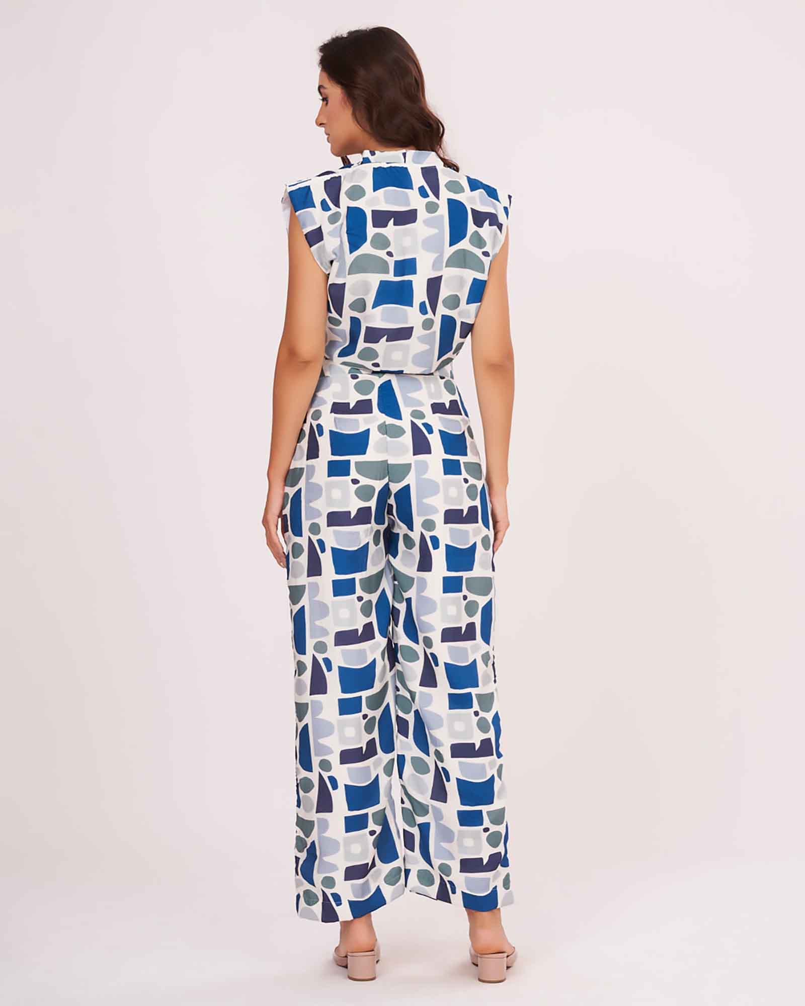 Rear view of the blue V-neck crop top and matching printed trousers, highlighting the back button and relaxed straight-leg pant fit.