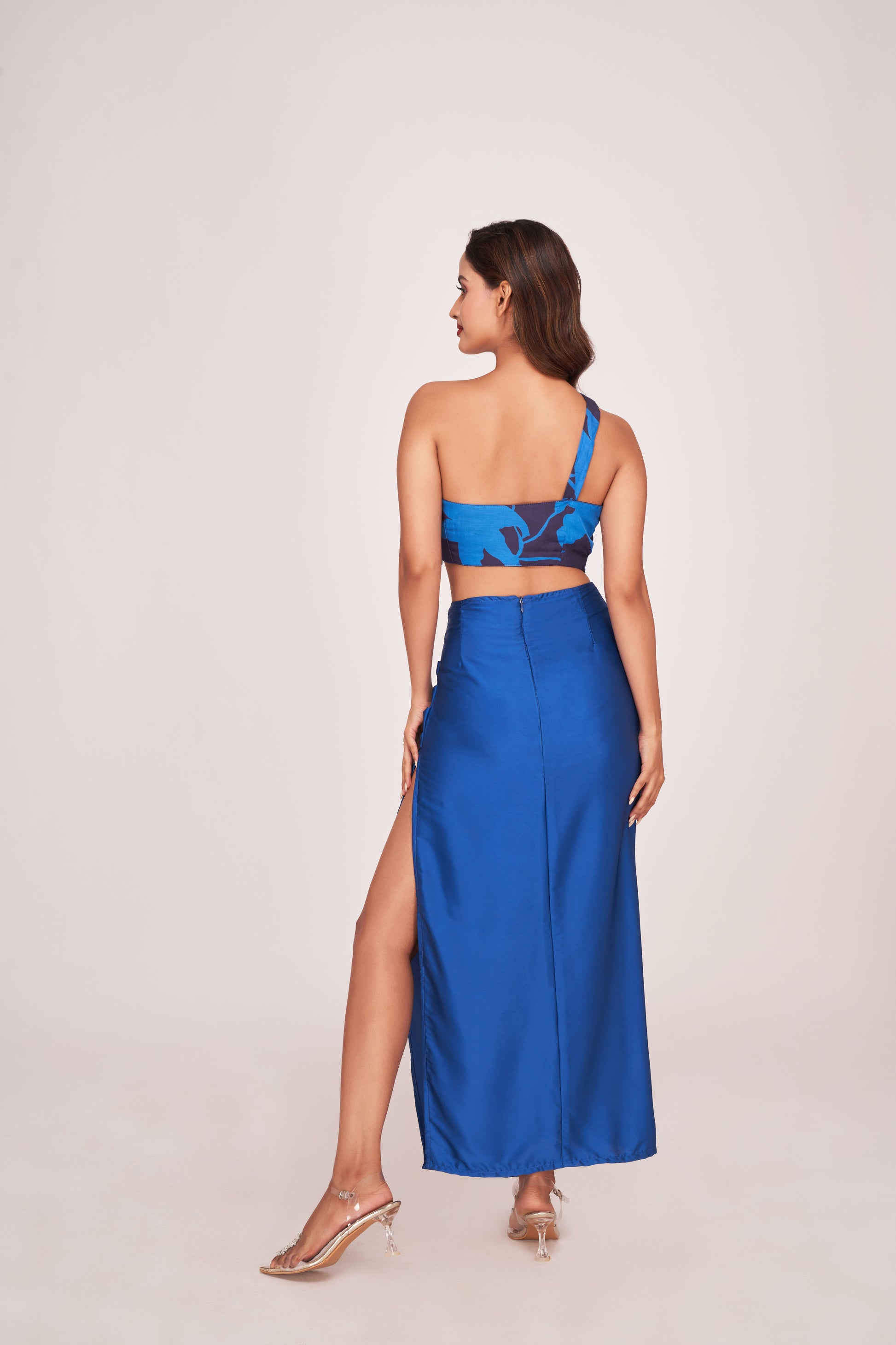 Rear angle showing the skirt's fit and one-shoulder crop top of the blue satin co-ord set.