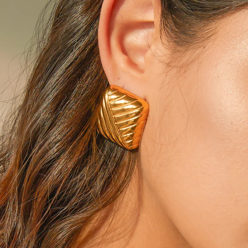 These striking gold geometric earrings offer a modern and architectural look that sits elegantly on the lobe, making them an ideal statement accessory for a gallery opening or a minimalist dinner outfit.