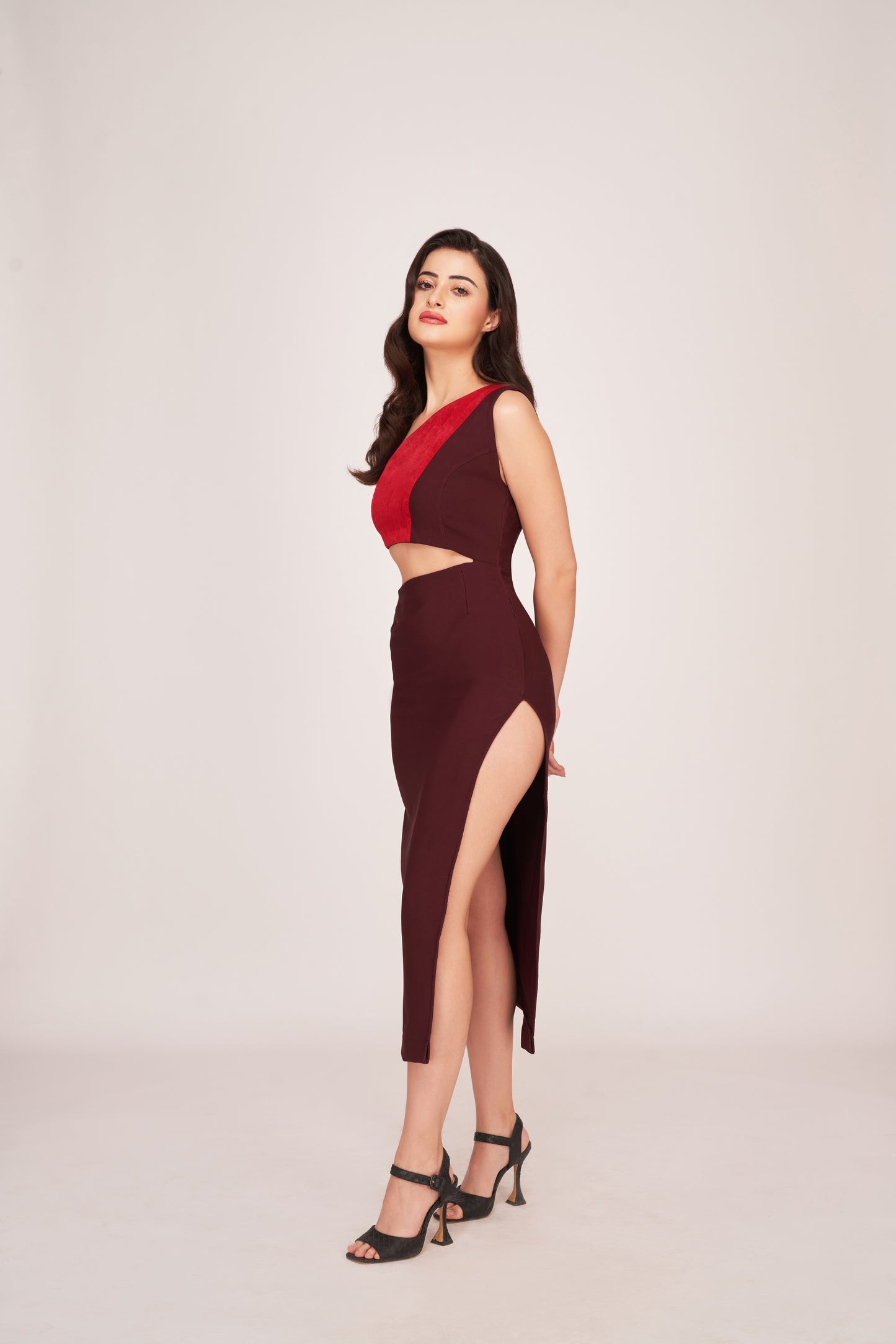 Model posing at an angle in a brown and red cut-out midi dress, showcasing the waist cut and side slit.
