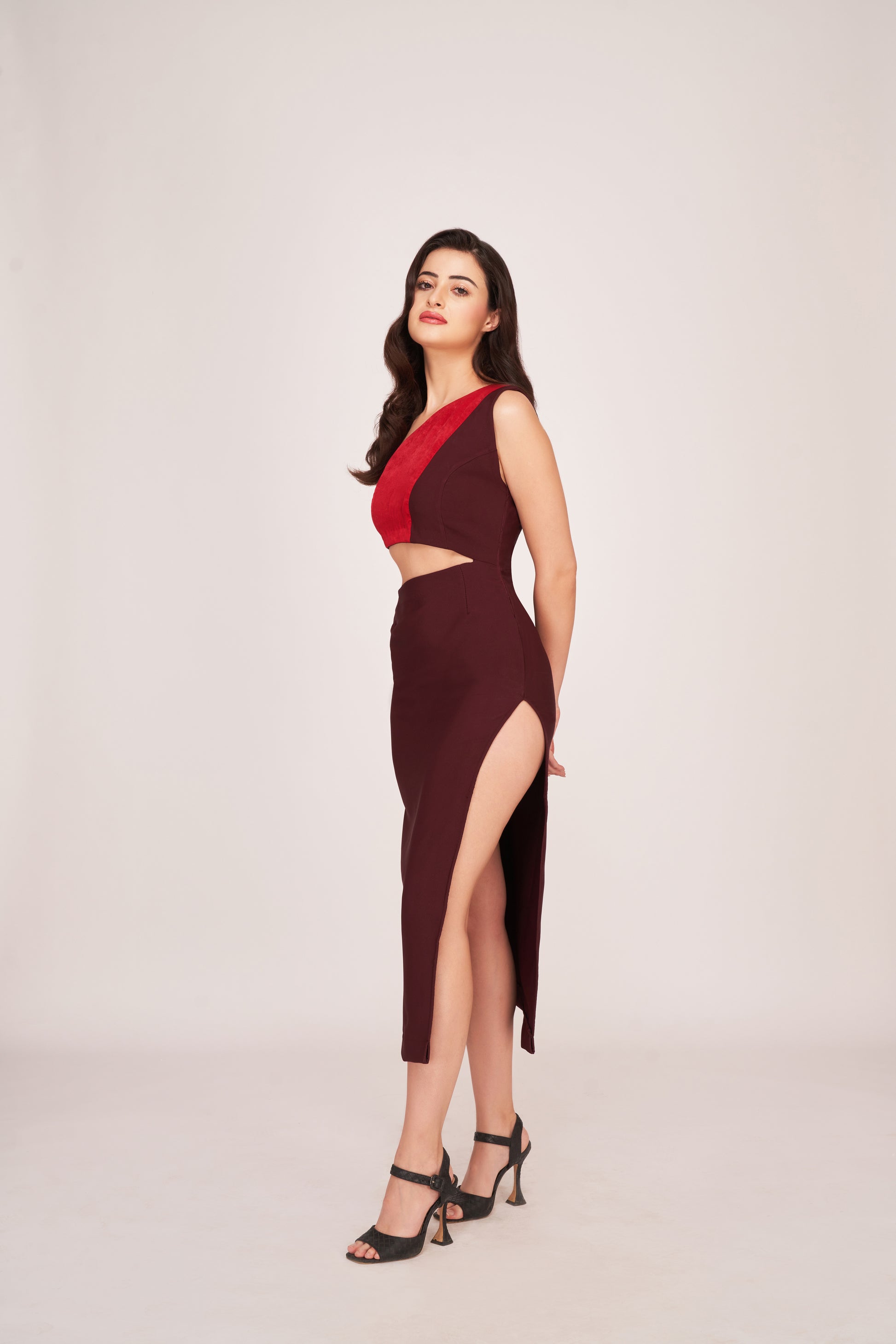 Model posing at an angle in a brown and red cut-out midi dress, showcasing the waist cut and side slit.
