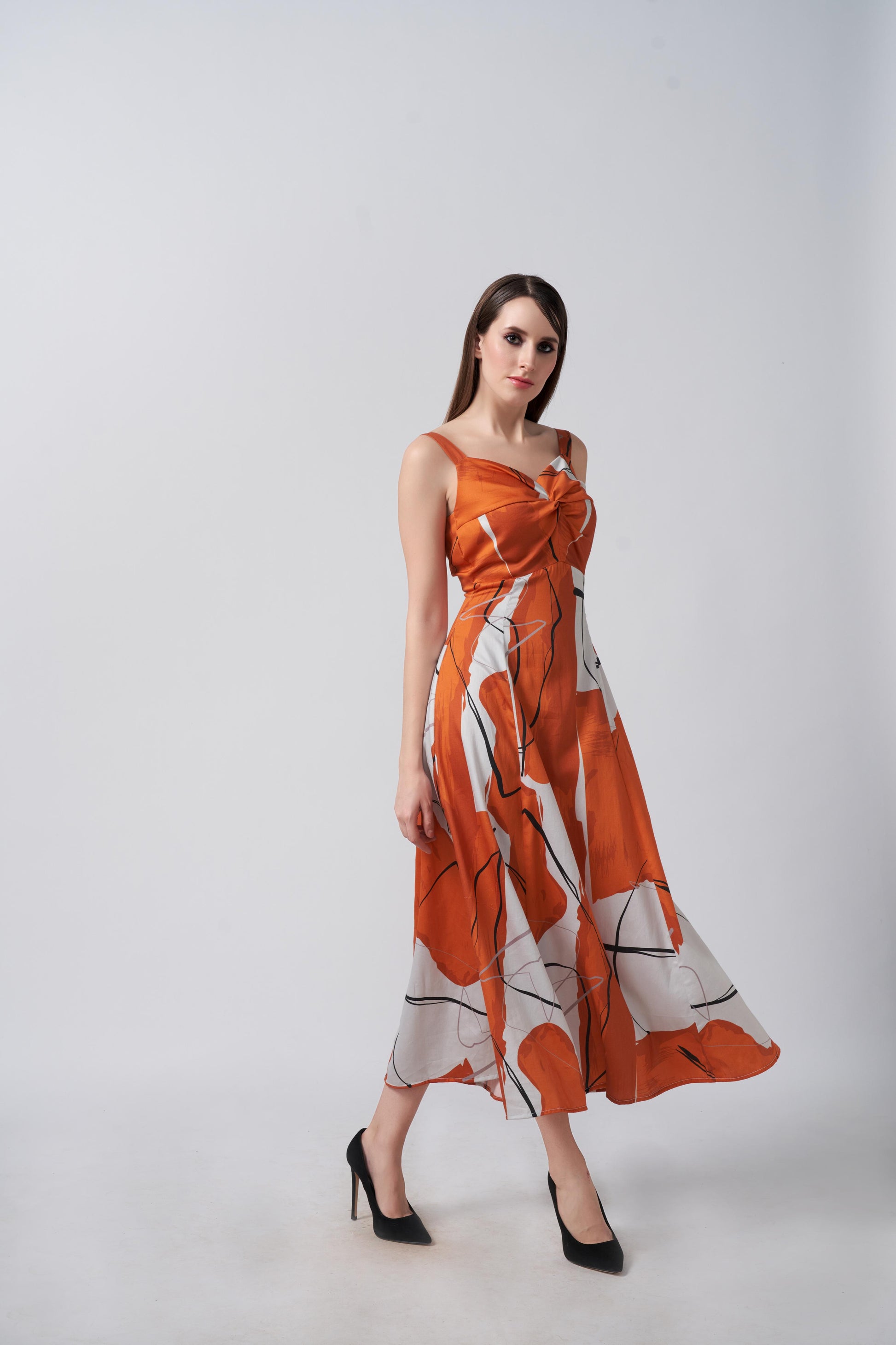 Model mid-walk in burnt orange and white midi dress, highlighting fabric movement and flattering silhouette.