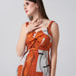Side profile of model in twisted neckline orange abstract dress, focusing on the fit and print.
