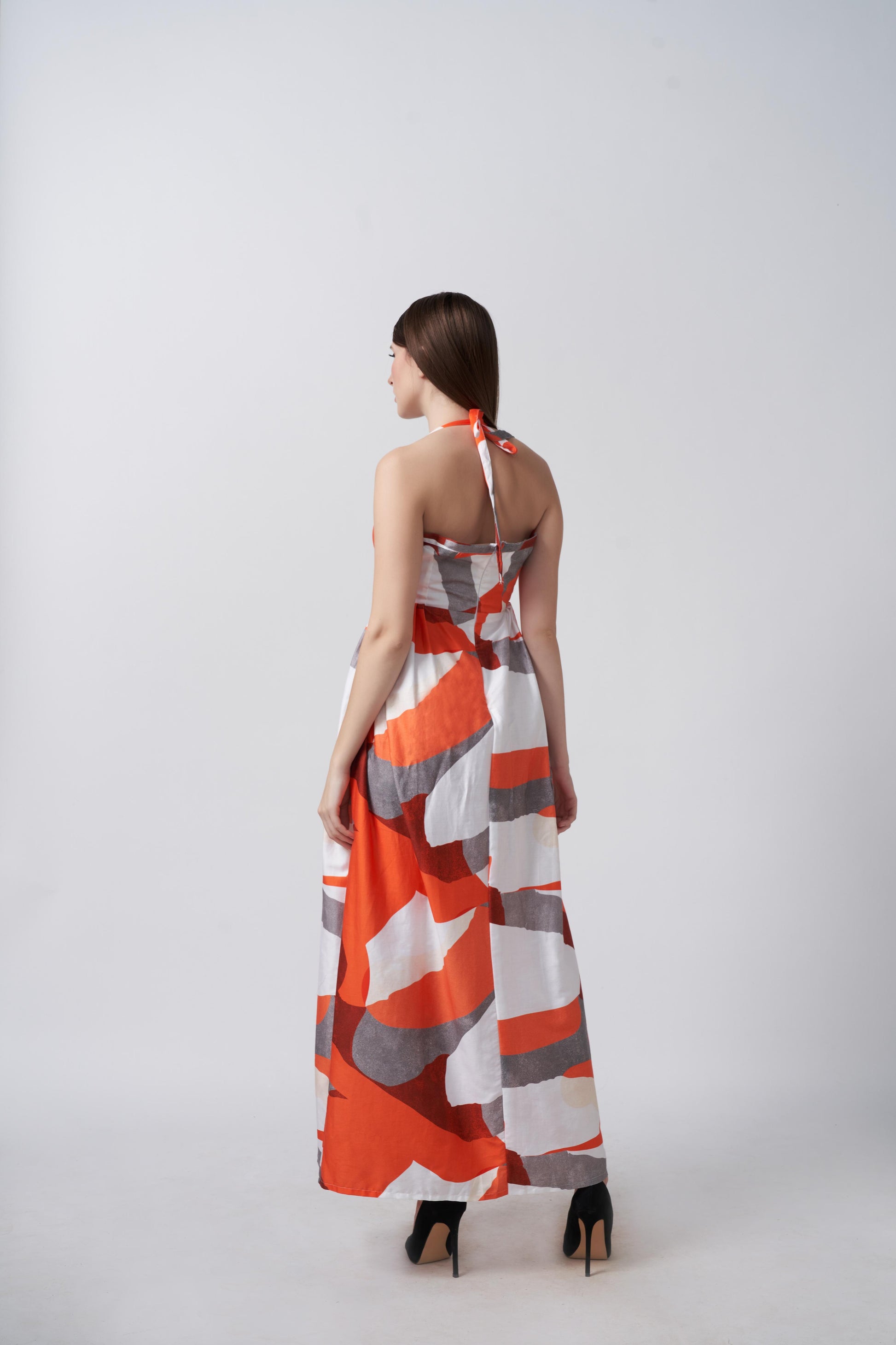 Back view of an ankle-length cotton satin dress with a halter tie-back neckline and fluid drape