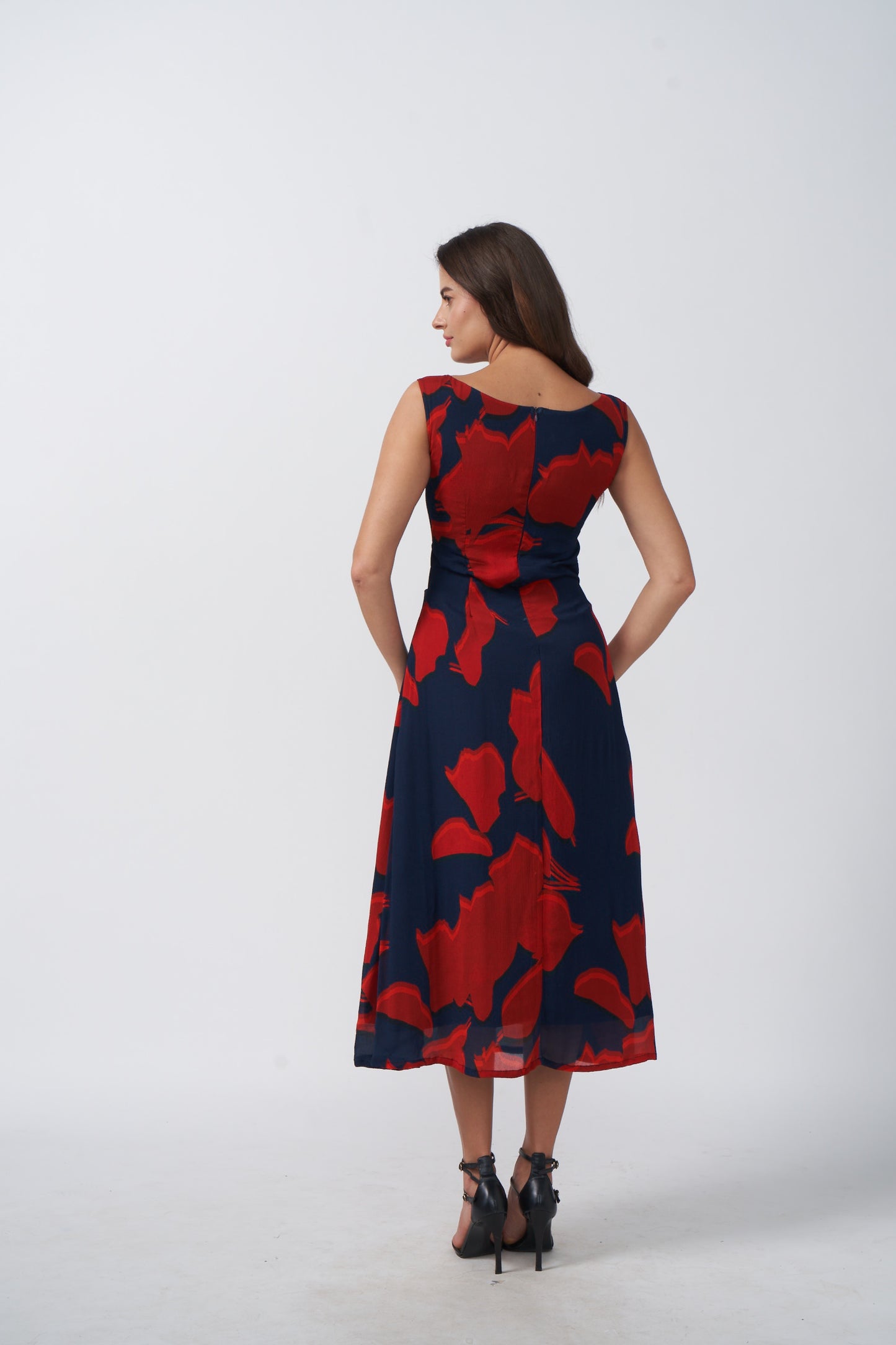 Back view of a sleeveless chinon midi dress with side waist cut-outs and a clean silhouette