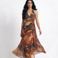 Lightweight Chinon maxi dress featuring a deep V halter neckline, open-back tie detail, and artistic rust, terracotta, olive, and slate blue print.