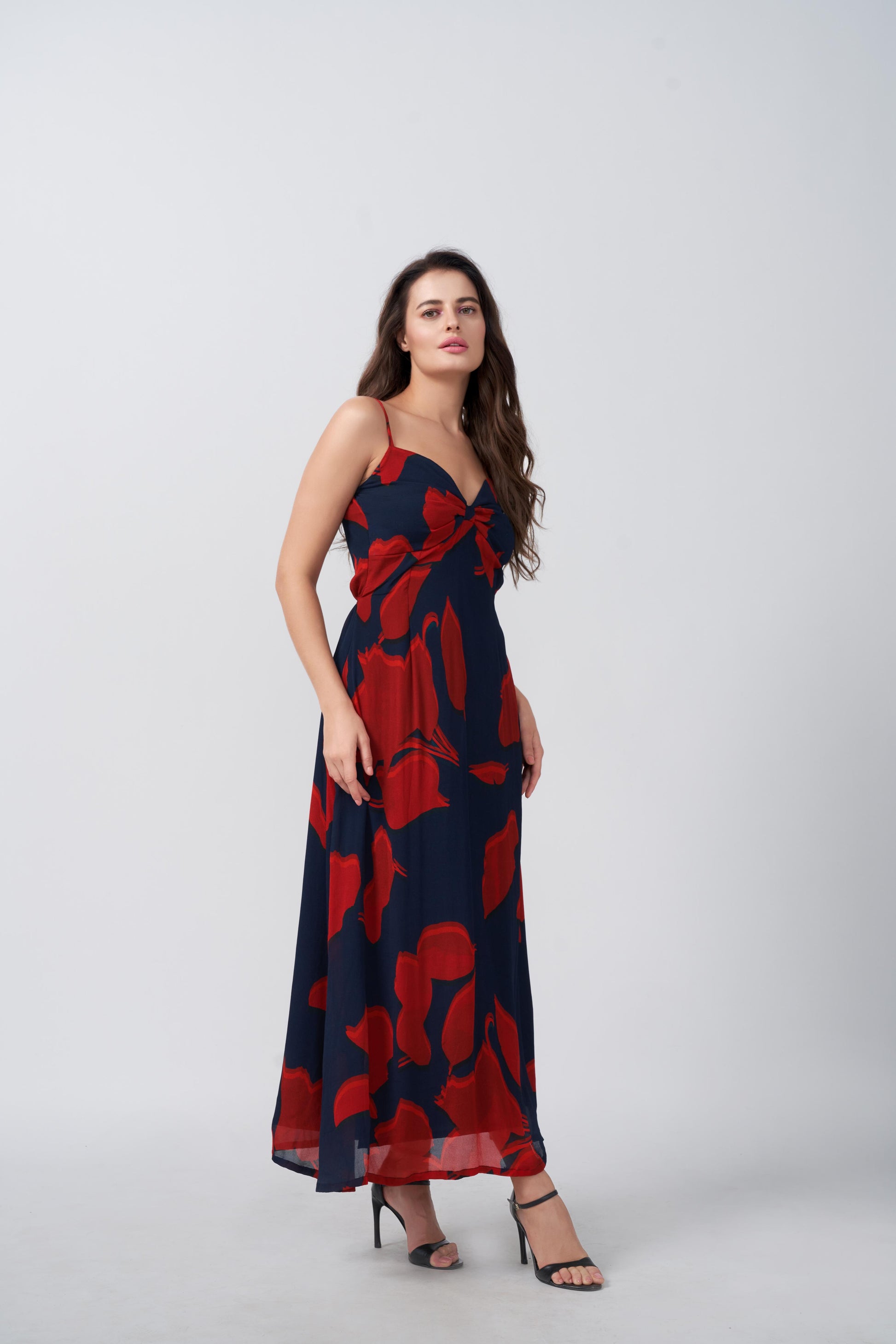 Model showing side profile of red and navy ruched chinon dress with ankle-length hemline.