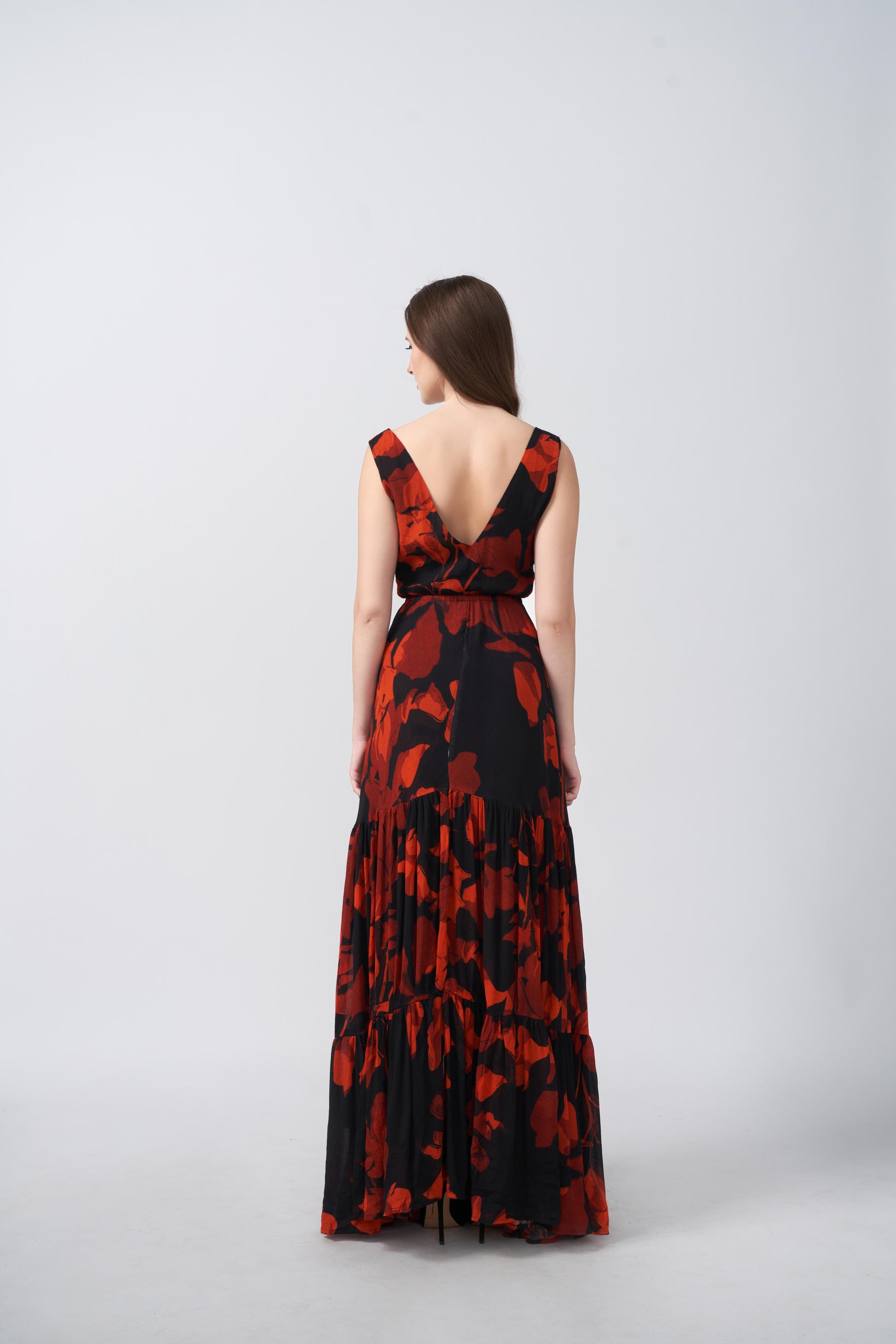 Back view of a full-length chinon dress with a tiered gathered silhouette and fluid drape
