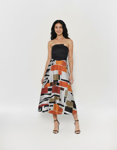 A-line silhouette dress showcasing a silky satin skirt with a bold geometric block print in vibrant orange, deep red, and neutral earth tones.