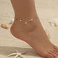 A dainty imitation gold titanium anklet featuring a shimmering crystal flower charm accented by elegant white pearls and grey beads, perfect for a sophisticated dinner date.