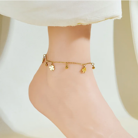A delicate gold-toned titanium anklet with alternating clover-shaped petal charms and small beads, perfect for adding a lucky, feminine touch to your brunch.