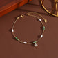 A dainty gold titanium anklet featuring a shimmering crystal flower charm accented by elegant white pearls and olive green beads.