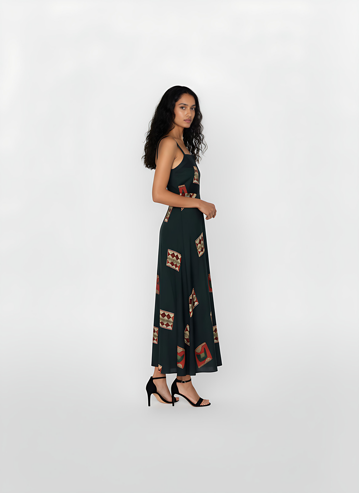 Ankle-length deep green crepe dress with wide shoulder straps, a notched square neckline, and geometric motifs in rust, beige, and maroon.