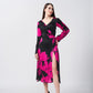 Model posing with hands on waist in silk midi dress with long sleeves and floral print in black and pink tones.