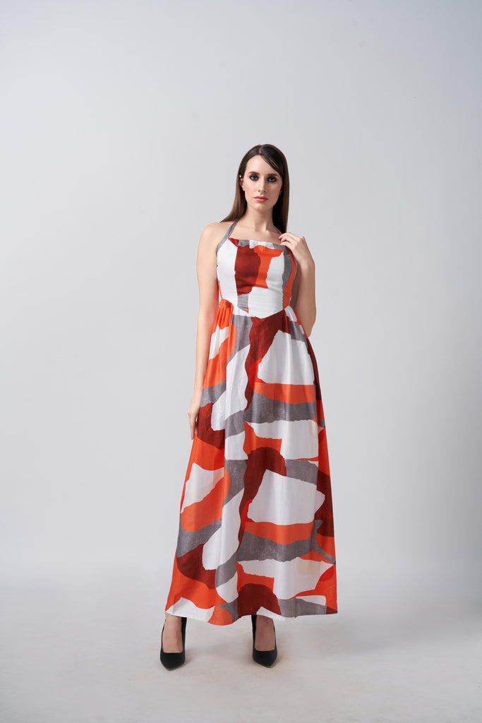 Model wearing an ankle-length cotton satin dress with orange and grey abstract print, standing against a plain background.