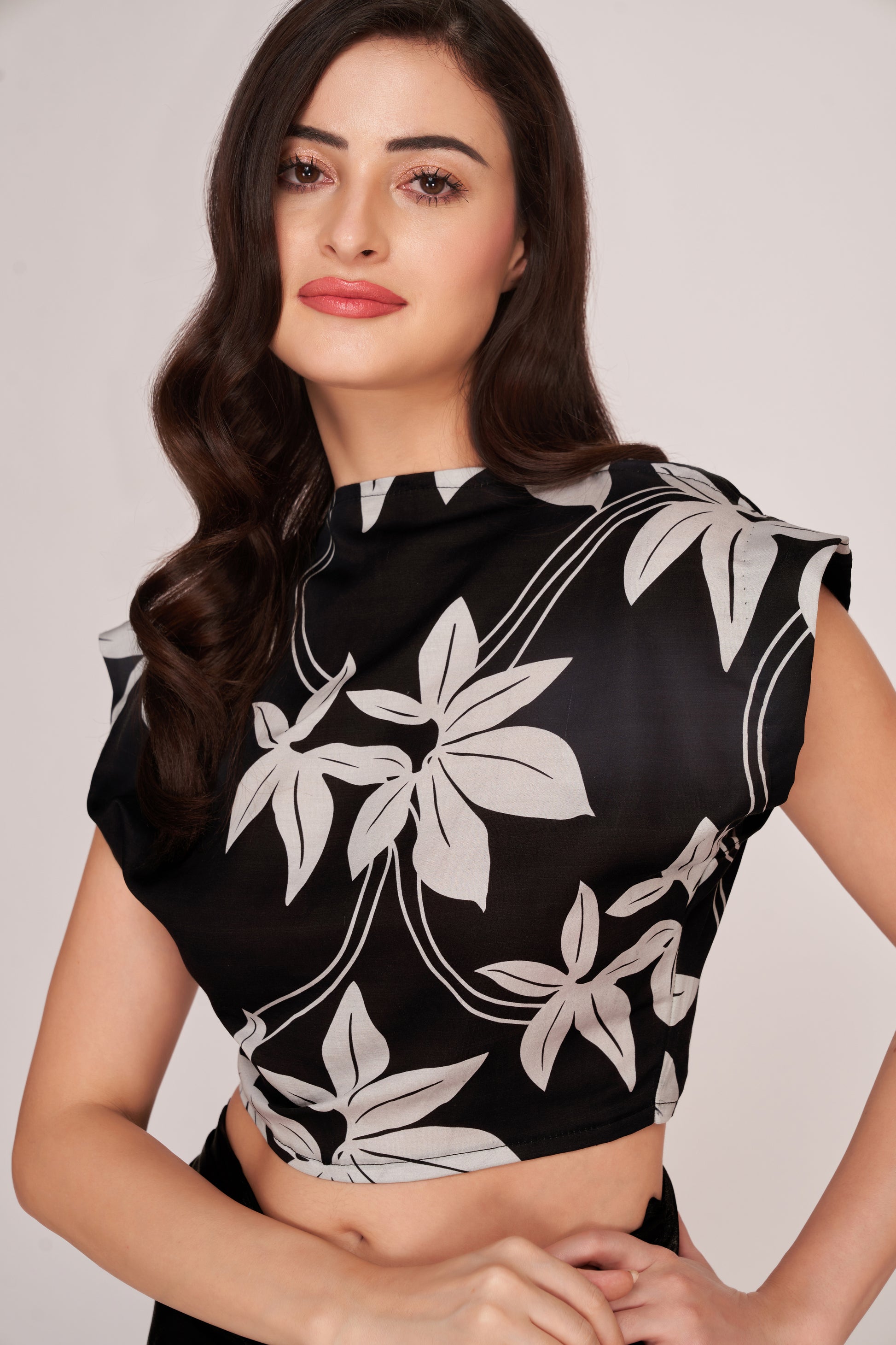 Close-up of the broad-shouldered floral crop top in black satin, highlighting the neckline and sleeve structure.