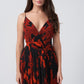 Model in a red and black floral chiffon dress with spaghetti straps, standing indoors