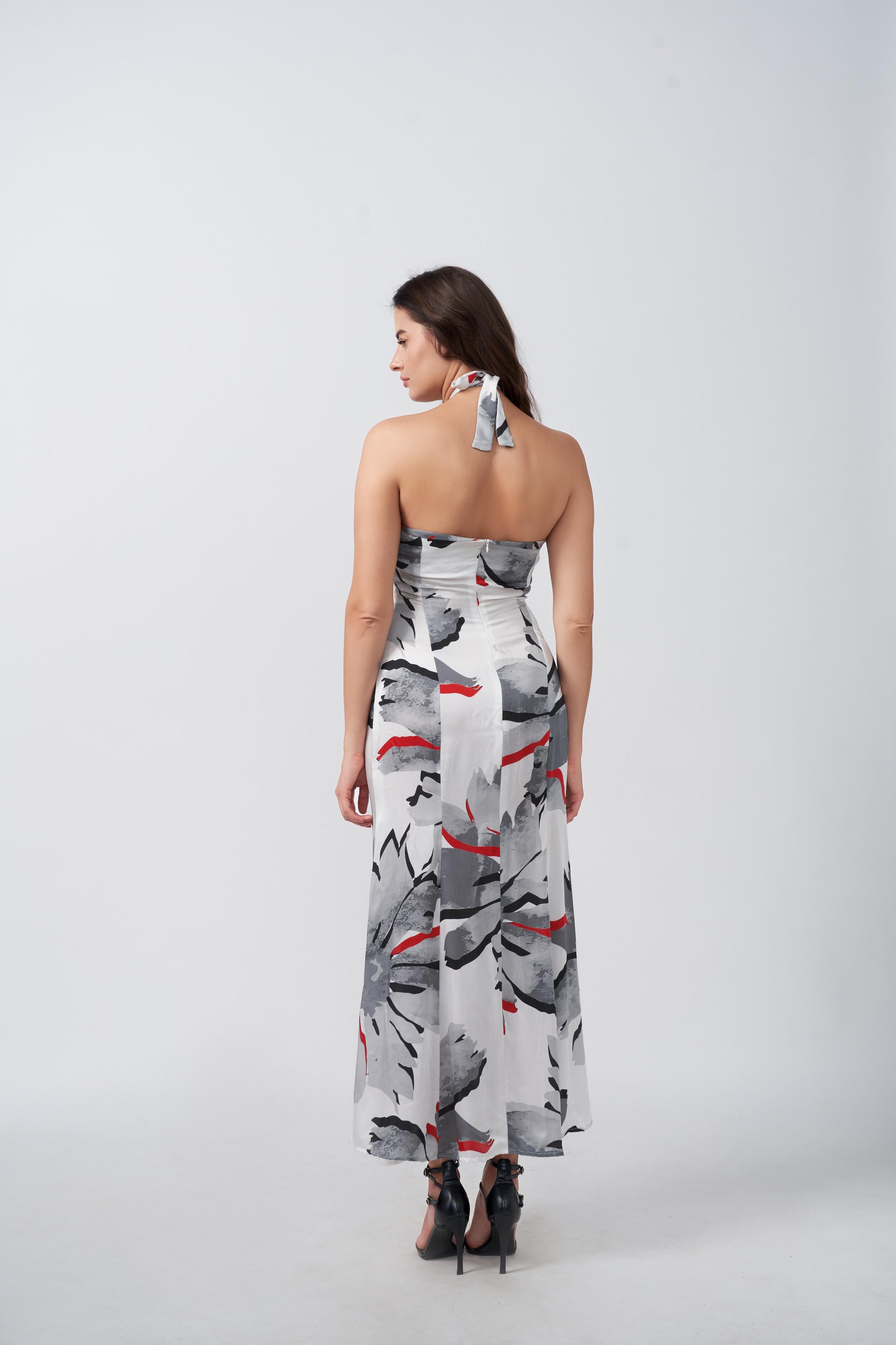 Back view of model wearing satin floral dress, highlighting halter tie-back neckline and elegant fit.