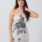 Close-up of model smiling candidly in halter neck satin dress with grey and red floral print.