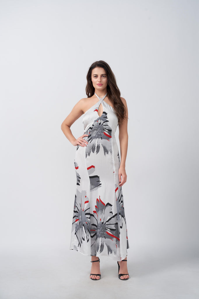 Model in a white and grey ankle-length satin dress with halter neck and red floral accents, standing front-facing.