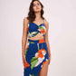 Front-facing pose with relaxed arms, showing the floral print detail and ruched bodice design of the blue halter neck top.