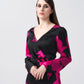 Close-up of model wearing V-neck pink and black floral silk dress, showing neckline and sleeve detail.
