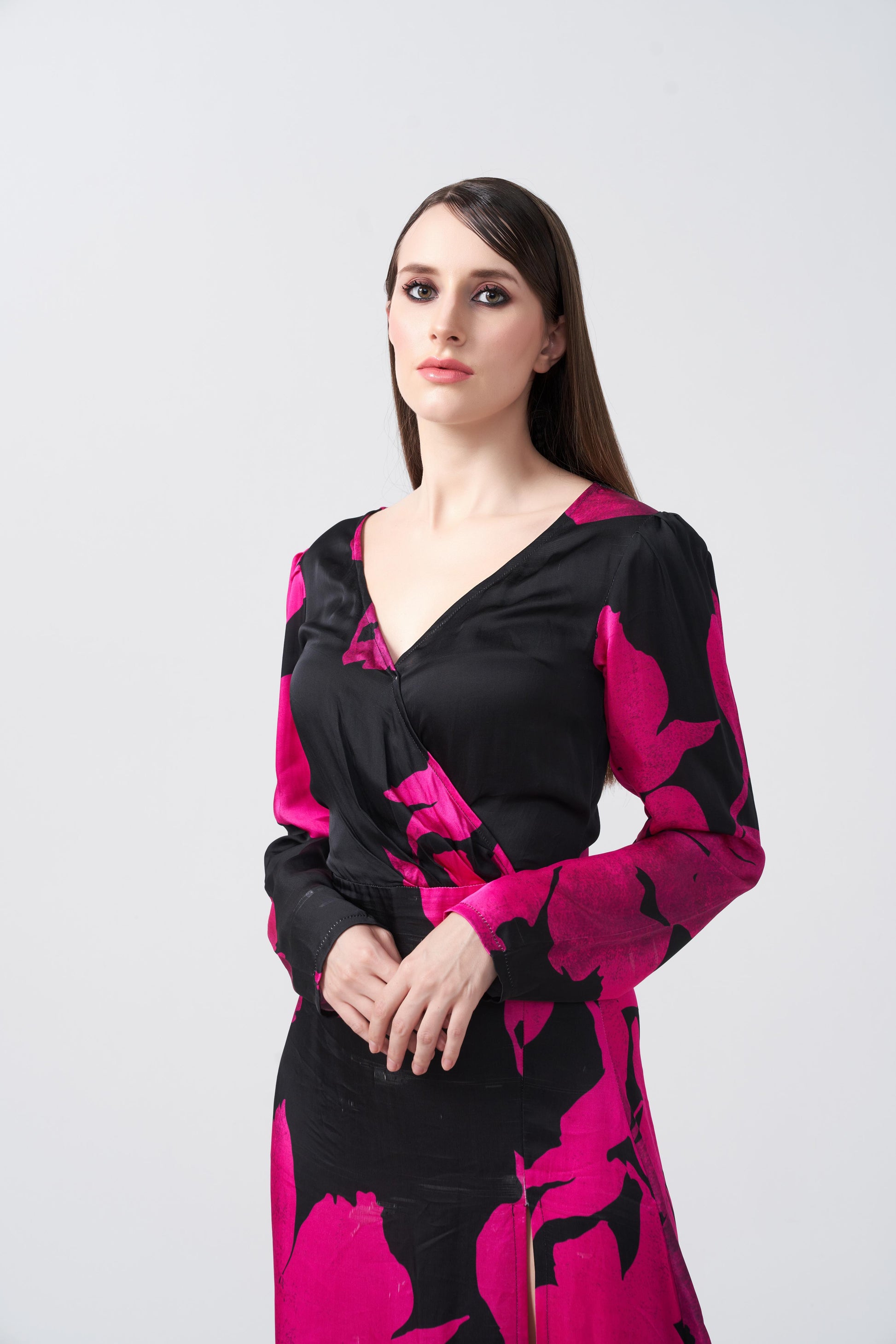 Close-up of model wearing V-neck pink and black floral silk dress, showing neckline and sleeve detail.