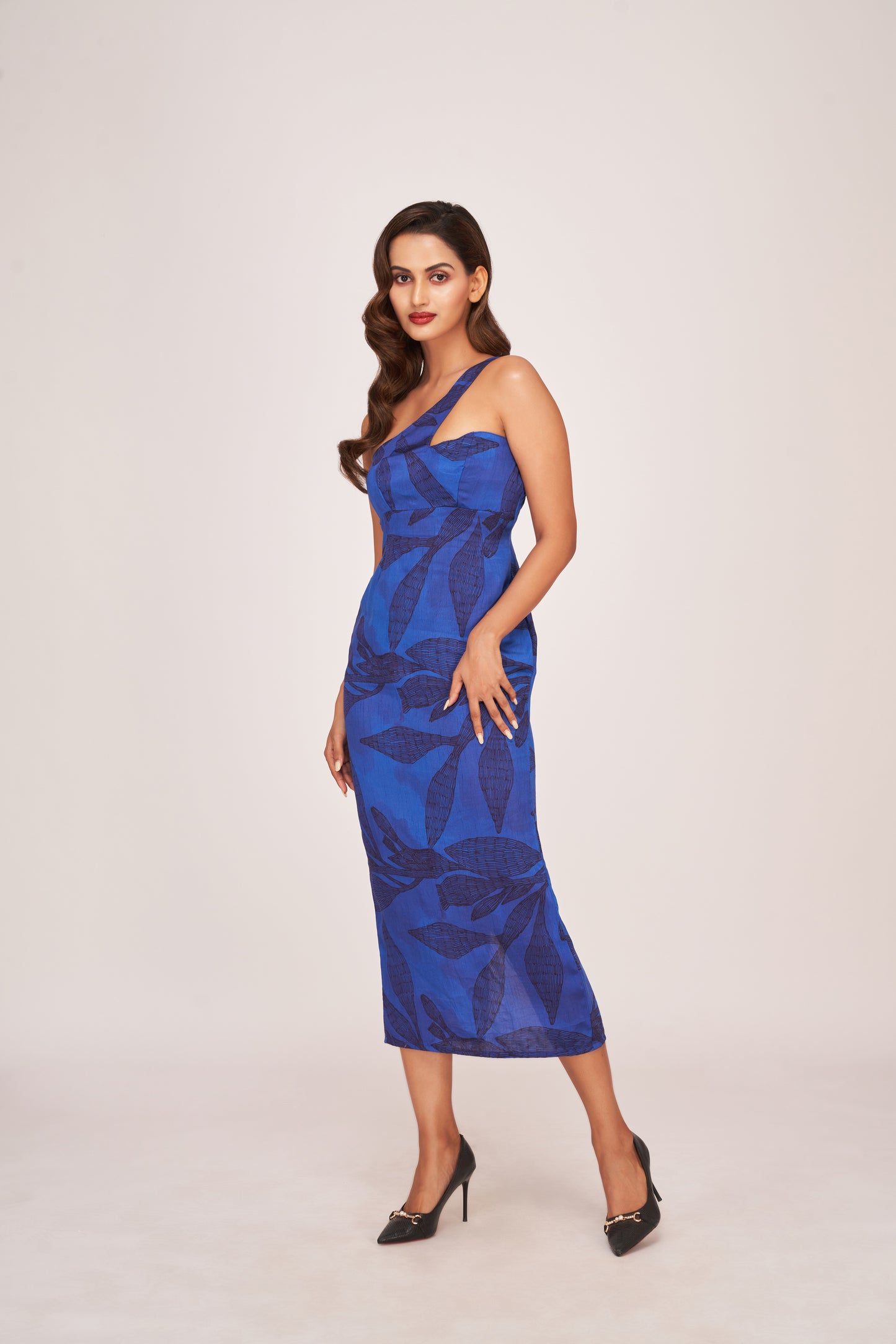 Full-length walking pose of model in one-strap silk dress with fitted silhouette and digital floral pattern.