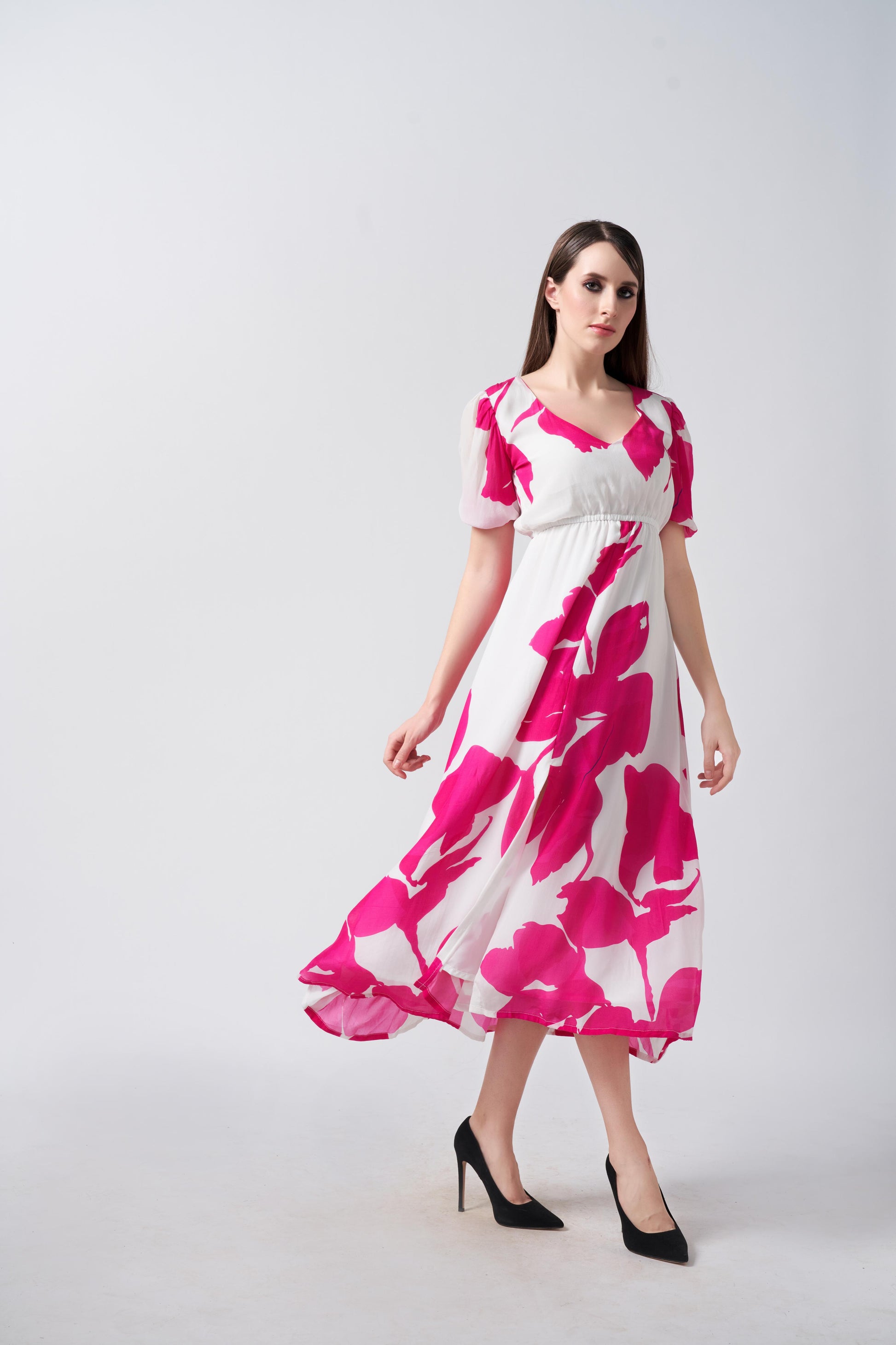 Model walking in a pink and white V-neck midi dress with puff sleeves, showing graceful movement.