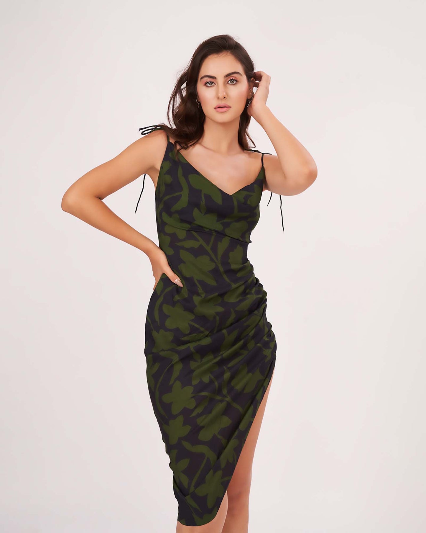 Walking pose of the model in green printed dress with strap shoulders and side split, showing movement and ruched detail.