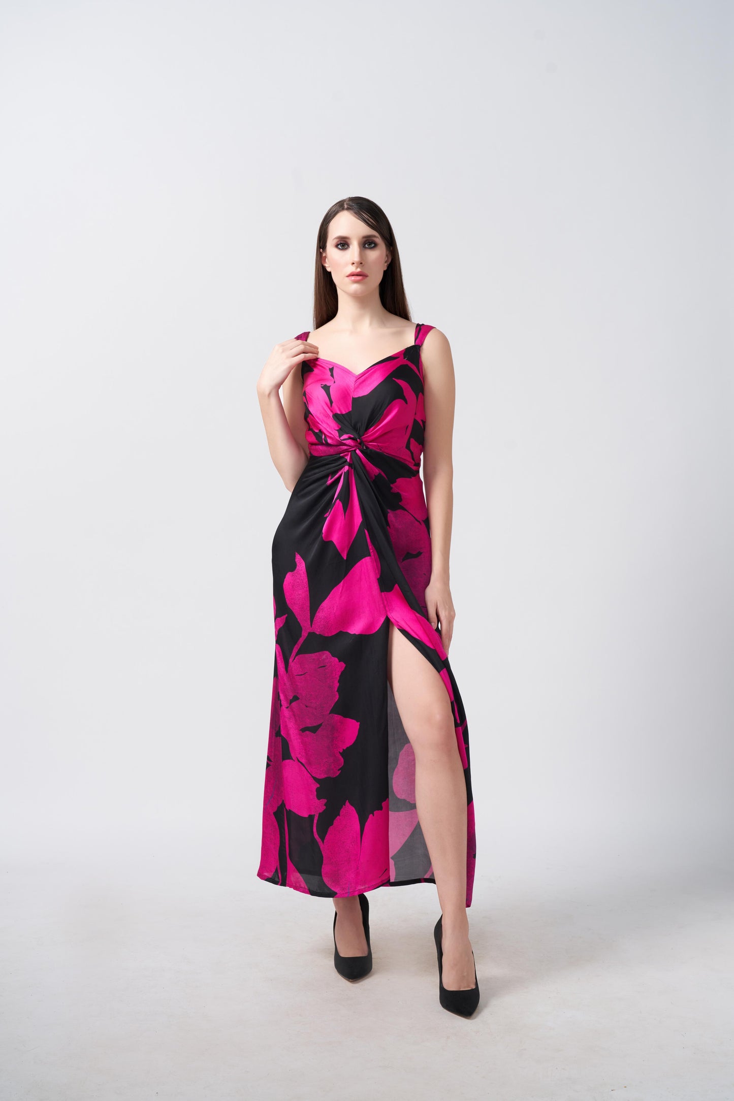 Model in a pink and black floral satin dress with front slit and knot detail at the waist.
