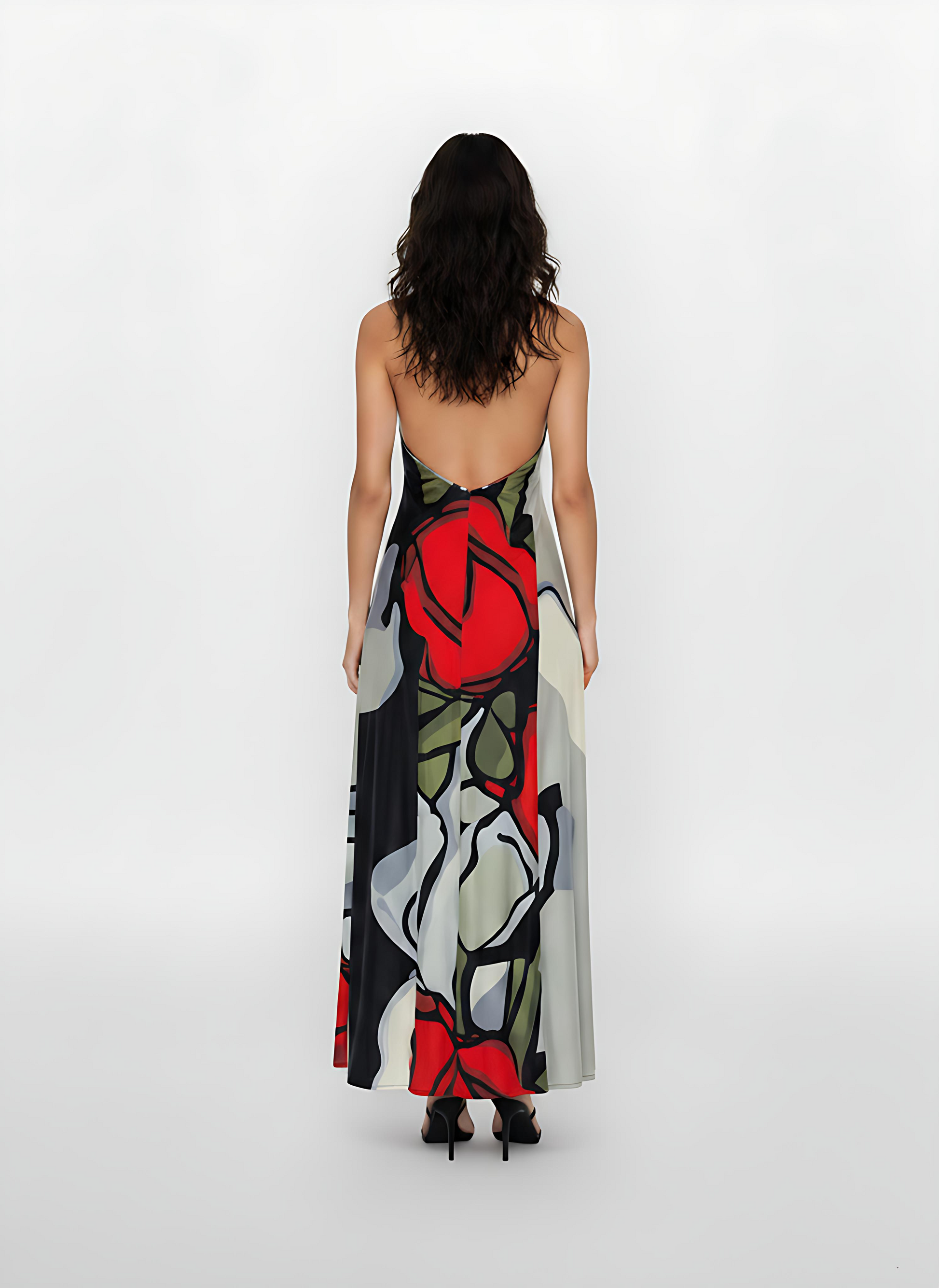 Back view of a model wearing a floor-length, backless halter maxi dress. The fabric features a bold, large-scale abstract floral print with prominent red roses and grey-toned petals.