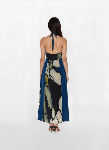 Backless maxi gown with a delicate halter tie that emphasizes a dramatic open-back design. The smooth, airy fabric is patterned with large-scale botanical shapes offering a breezy yet elegant feel for high-end resort wear. . 