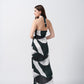 Back view of the model in green, black, and white satin dress with tie-back halter neckline and asymmetrical hemline.