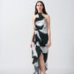 Full-length front view of the model walking in the satin abstract print dress with halter neckline and asymmetrical hem.