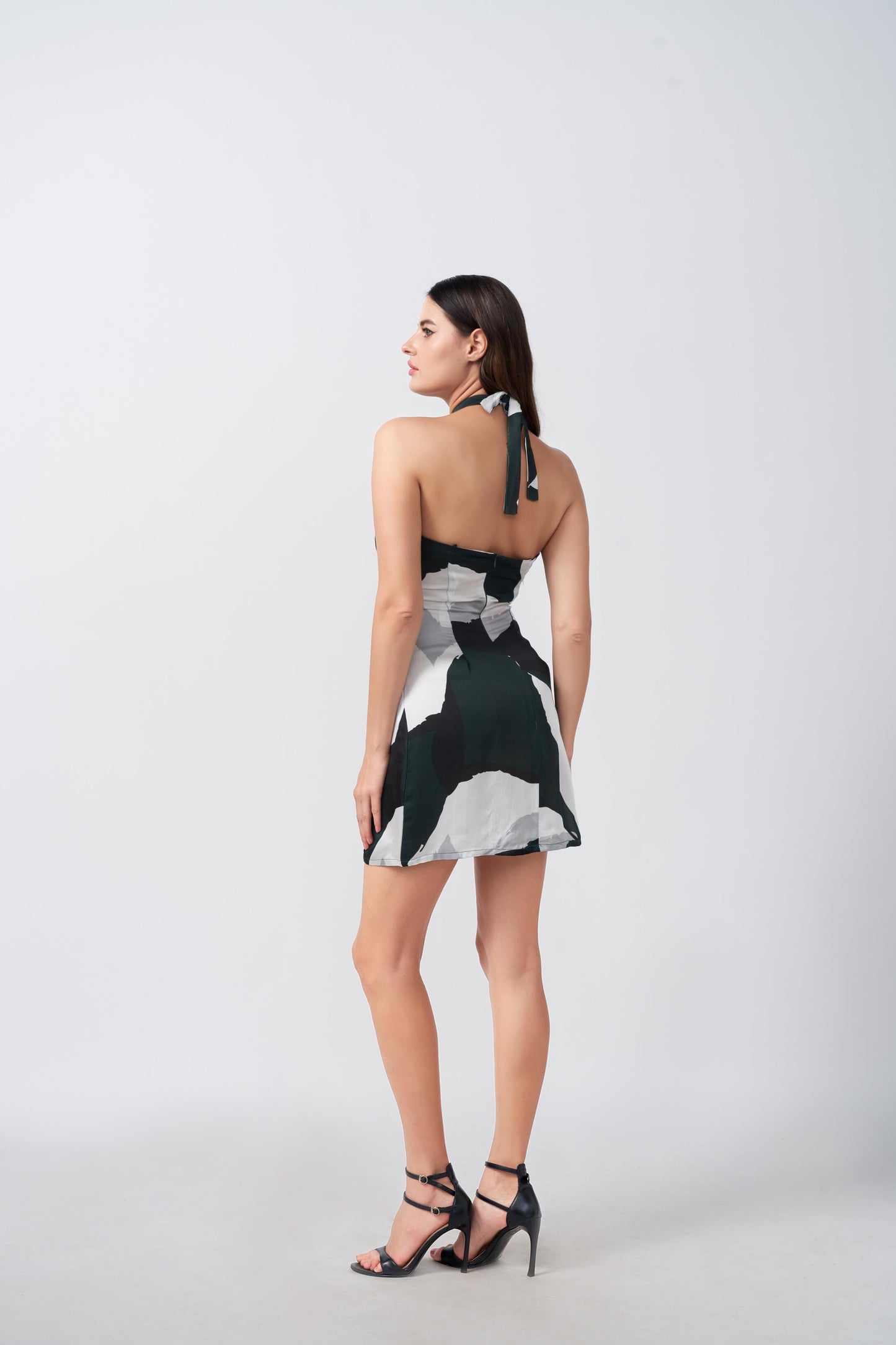 Rear view highlighting halter tie-back and back fit of green and black abstract print dress.