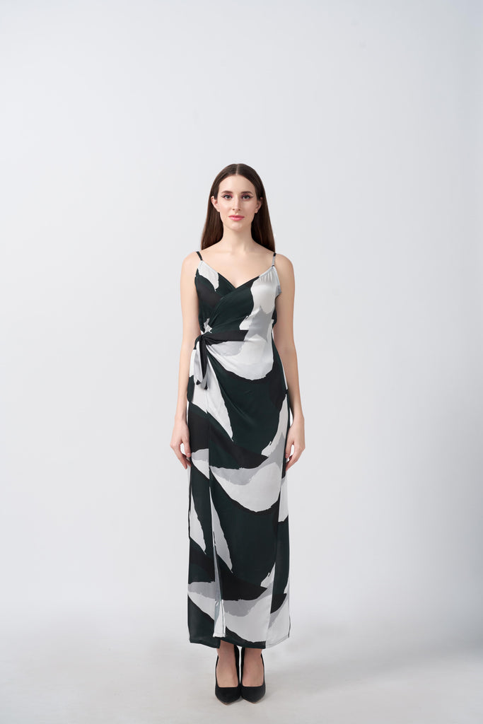 Model standing in a sleeveless ankle-length satin wrap dress with dark green, grey, and black abstract print.
