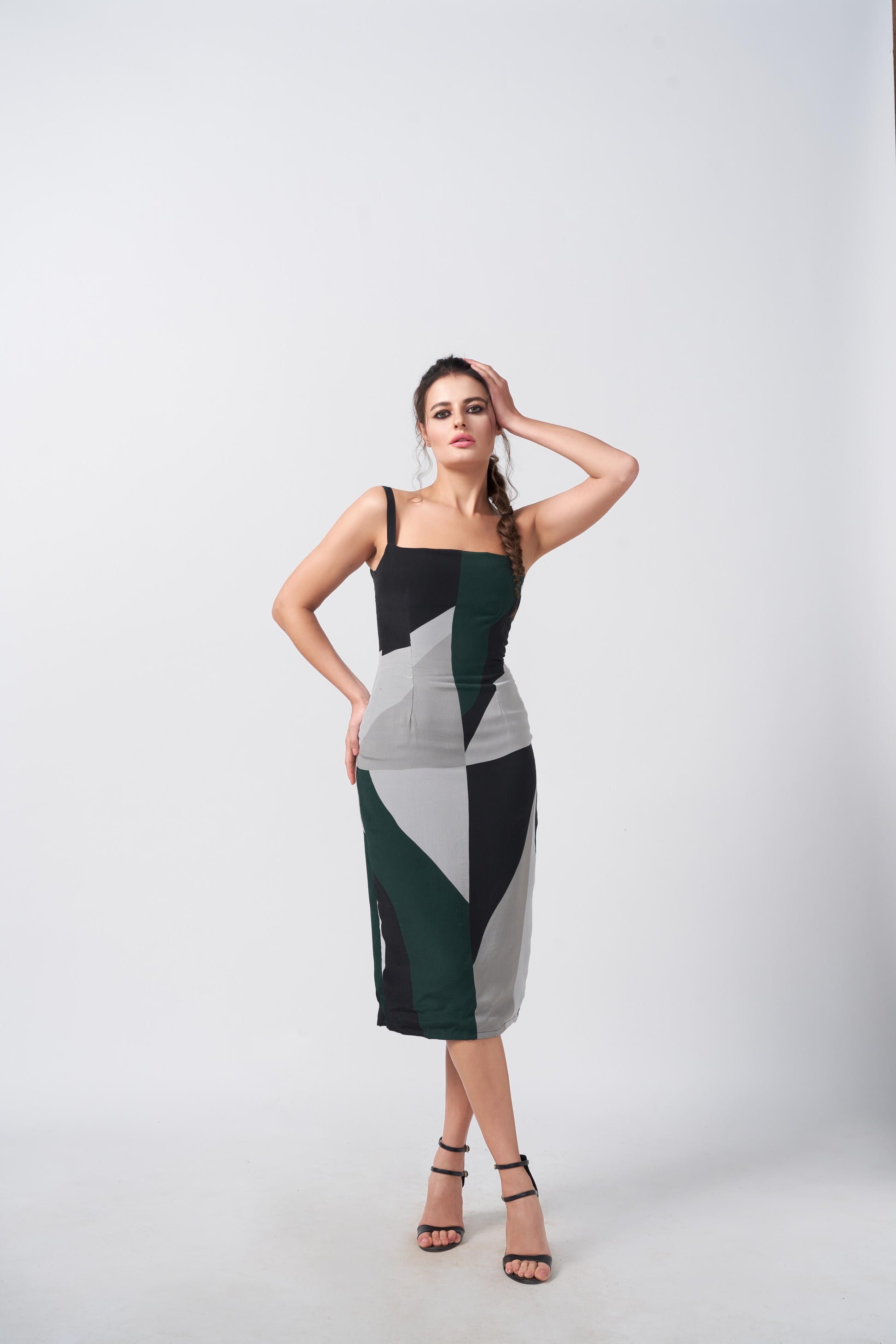 Model posing with hand on waist in abstract square-neck midi dress, showcasing the fitted bodice and color-block pattern.