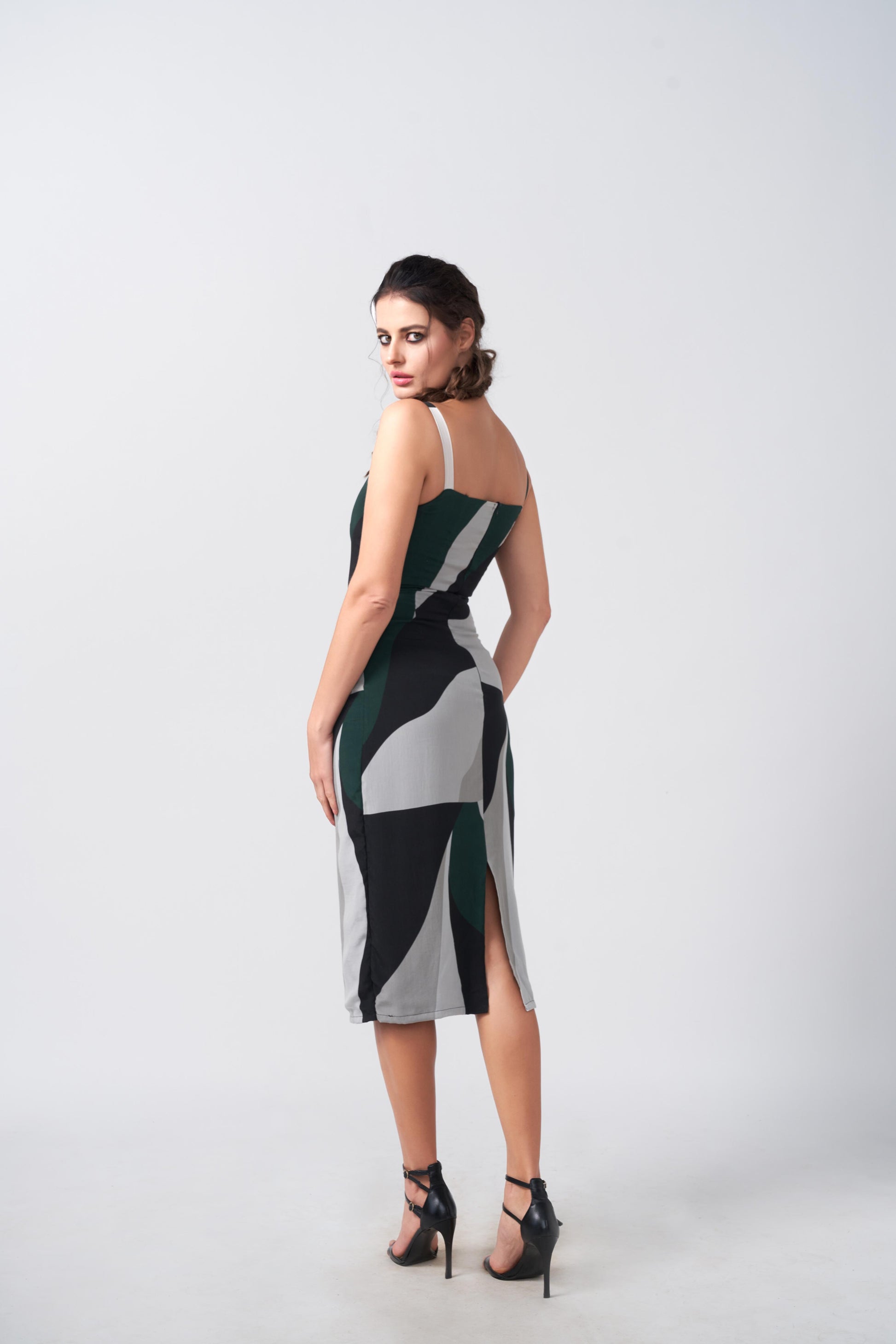 Model in side stance wearing abstract crepe dress with square neckline, emphasizing the contour fit and graphic design.