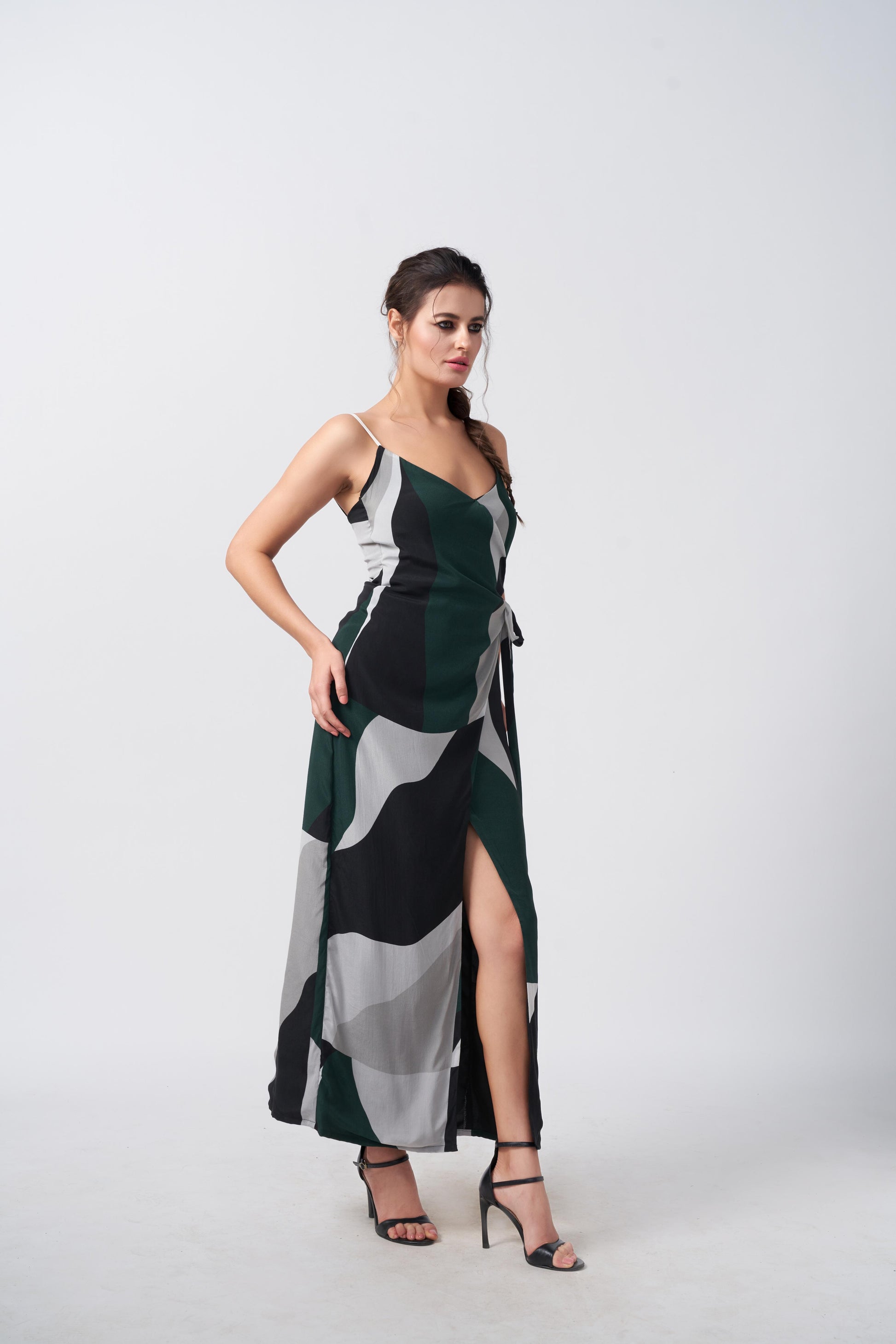 Side profile of model in spaghetti strap wrap dress with green and black abstract pattern, showcasing relaxed drape.