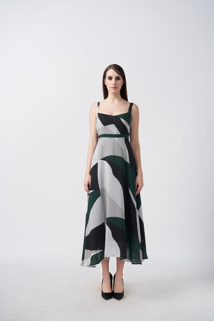 Model facing front in a green, black, and grey abstract print midi dress with delicate straps.