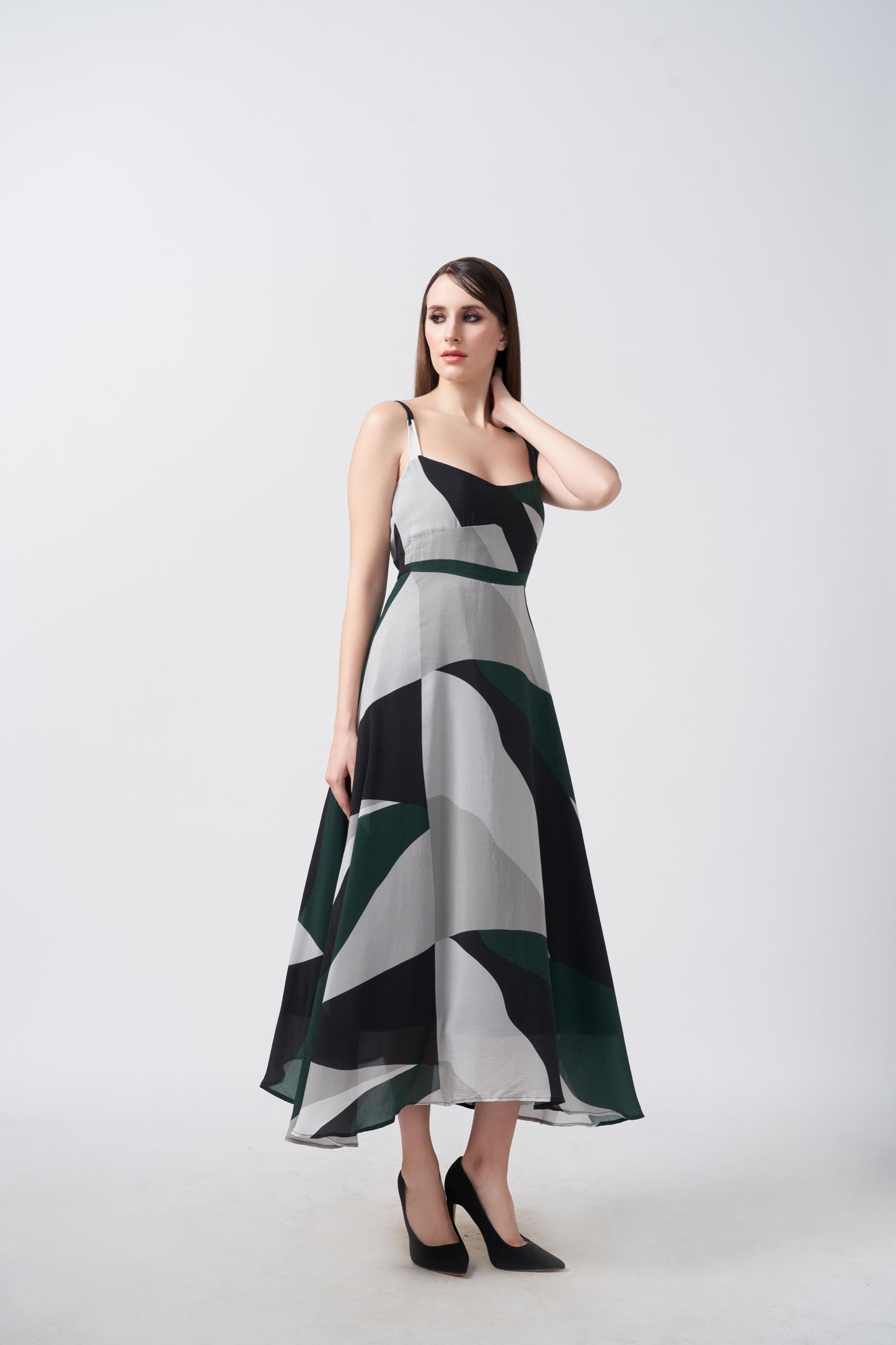 Model walking in studio in abstract print midi dress, showcasing fabric movement.