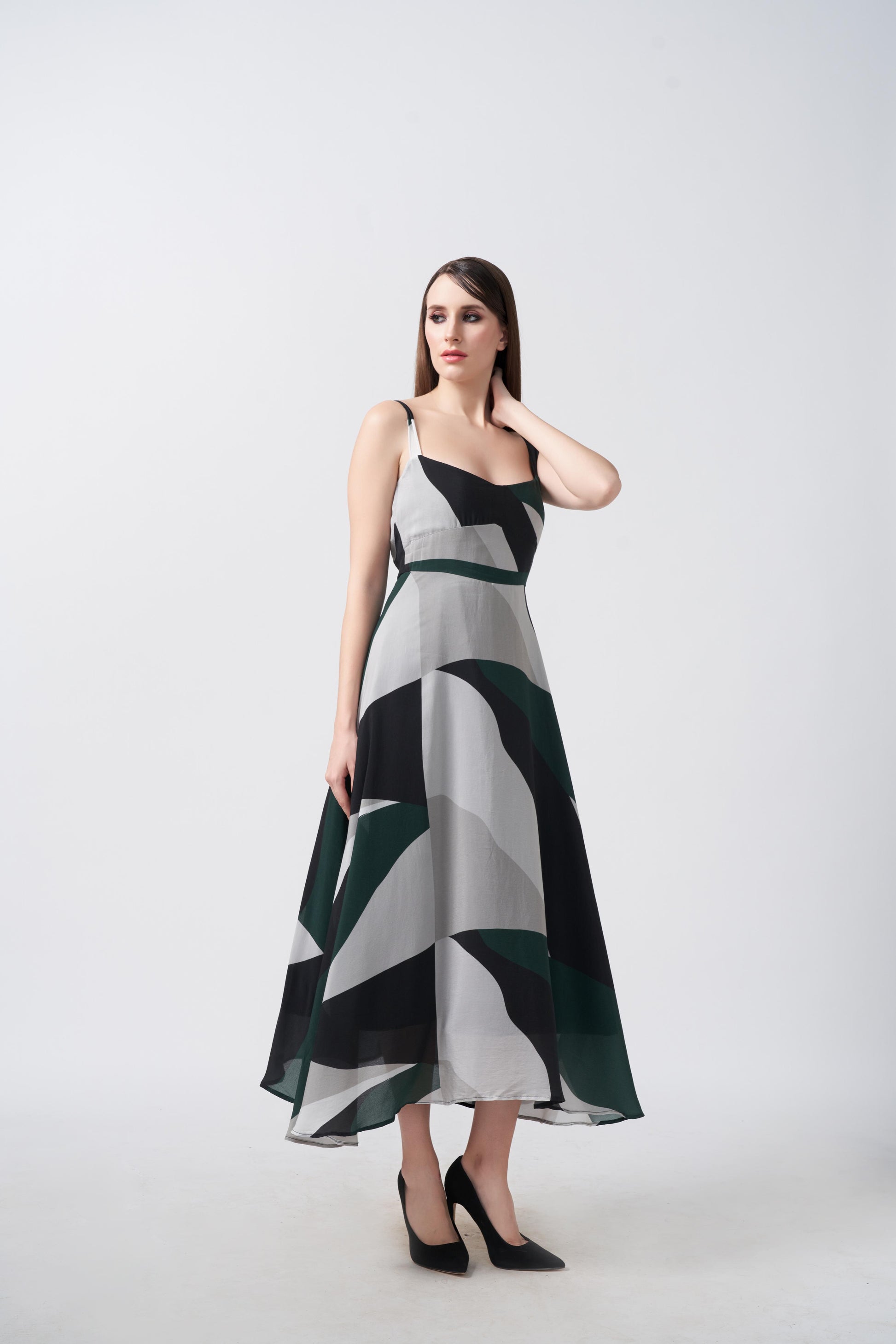 Model walking in studio in abstract print midi dress, showcasing fabric movement.