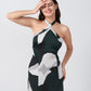 Close-up of model in halter tie-back green and black abstract print short satin dress.