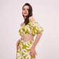Side-angled standing view with slight head tilt, showing pant slit and the relaxed drape of the wide-legged green co-ord trousers.